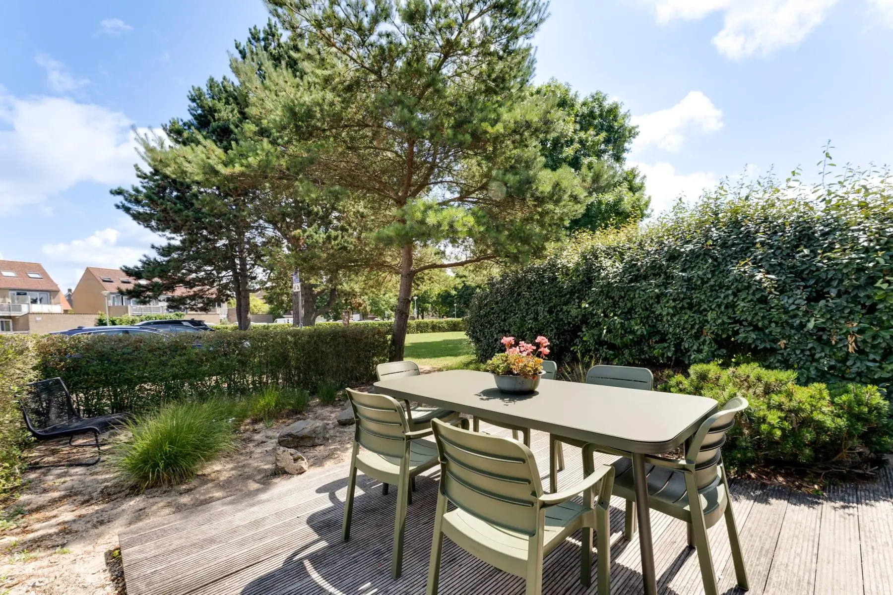 Tuintafel met stoelen op de vlonder tussen de duinbeplanting
